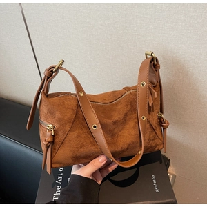 Close-up of caramel suede handbag showing adjustable leather strap and metal hardware