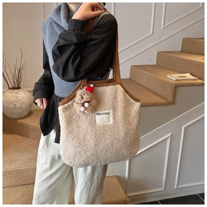 Detail der beigen Plüschtasche mit SEEYOU-Logo und Bärenanhänger von einem Model getragen