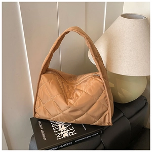 Detailed view of caramel brown quilted puff shoulder bag on an aesthetic book display