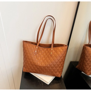 Detail shot of brown quilted tote bag showing diamond stitching and metal rivets