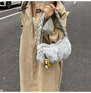 Detail of grey plush faux fur shoulder bag with braided handle and beaded charm detail