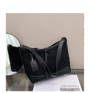 Detail of matte suede and glossy leather patchwork on black crossbody bag with gold hardware