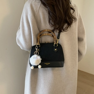 Detail view of black suede crossbody bag with vintage bamboo handle and cute chick pendant
