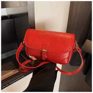 Close-up of red pebbled leather crossbody bag with buckle detail and textured finish