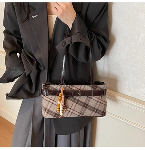 Detail of vintage plaid underarm bag with faux leather strap and beaded charm accent