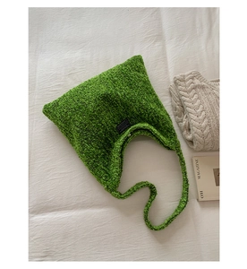 Detail van groene wollen texture tote bag met modelabel op witte stoffen achtergrond