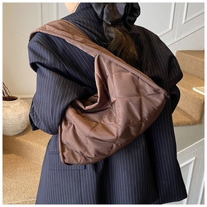 Quilted caramel brown shoulder bag with rhombic pattern shown on a model's shoulder