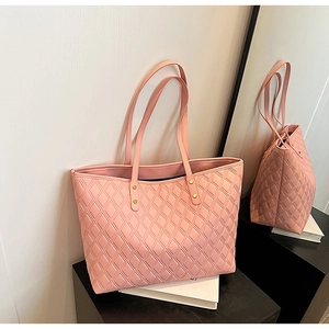 Detail of pink quilted tote bag showing large diamond stitching and gold metal buckles