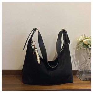 Détail du grand sac cabas en daim noir avec bandoulière en cuir et breloque perlée