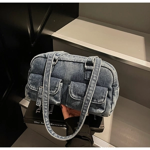 Detail view of blue denim shoulder bag with two front pockets and vintage metal buckles