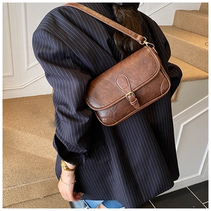 Detail of vintage brown crossbody bag with metal buckle on navy blue blazer outfit