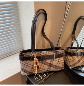 Close-up of brown plaid underarm bag with vintage leather straps and decorative beads