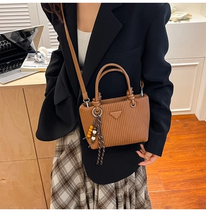 Détail du sac seau en velours côtelé marron avec anses en cuir et pompon perlé