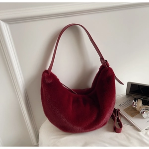 Close-up of deep red faux fur hobo bag with leather strap and plush texture