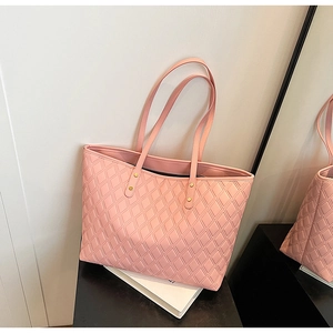 Close-up of pink quilted tote bag with matte texture and gold rivet hardware details