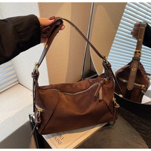 Detail of dark brown suede handbag featuring golden metal zipper and textured finish