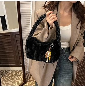 Close-up of black faux fur plush handbag featuring unique braided handle and bead charm