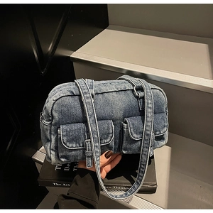 Detail of vintage blue denim bag with dual front pockets on a stack of books