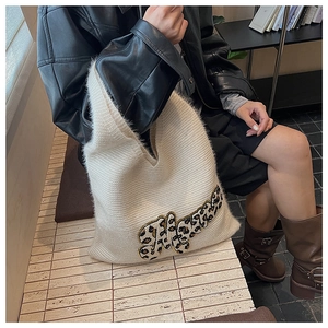 White fuzzy knit tote bag with leopard print letters styled in a cozy city setting