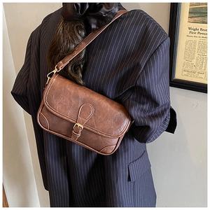 Close-up of brown vintage crossbody bag with textured leather and gold buckle