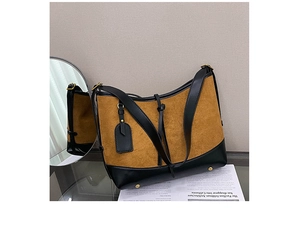 Detail of hobo bucket bag in brown suede and black leather patchwork with gold hardware