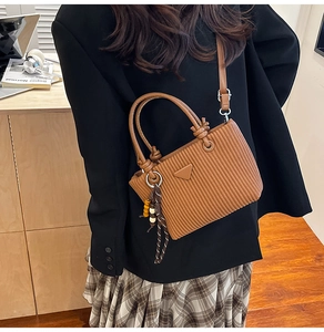 Détail d'un sac seau plissé marron avec logo triangle en métal et gland à perles