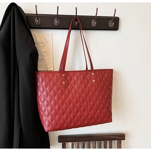 Detailed view of red quilted leather tote bag with elegant gold rivet and stitching