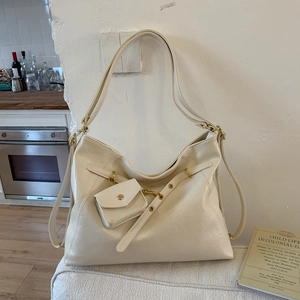Détail d'un grand sac Hobo crème avec mini porte-monnaie et bandoulière à œillets