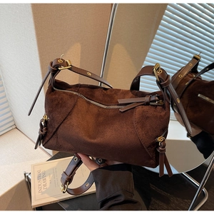 Close-up of vintage brown suede dumpling bag with metal zippers and adjustable strap