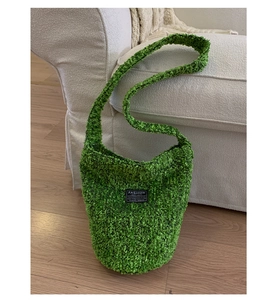 Detail einer flauschigen lindgrünen Beuteltasche mit Stricktextur und Logo-Aufnäher