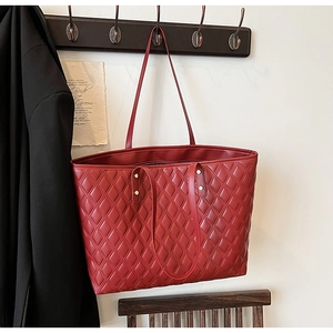 Detailed macro view of red quilted leather tote bag with classic rhombus pattern