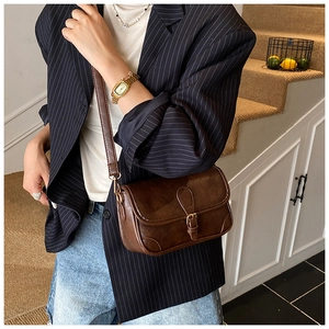 Close-up of vintage brown crossbody bag featuring golden buckle and detailed stitching