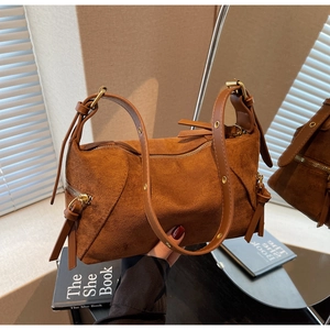Detail of brown suede dumpling bag featuring gold zipper and side drawstring accents