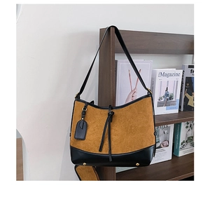Detail of vintage matte bucket bag hanging on a shelf featuring golden bottom rivets