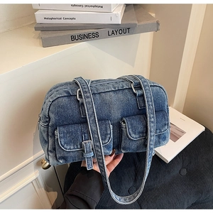 Detailed macro of vintage blue denim shoulder bag with dual buckled front pockets