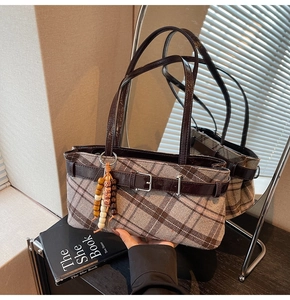 Close-up of vintage plaid underarm bag with decorative belt buckle and beaded charm