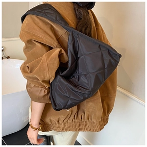Detail of black quilted shoulder bag featuring premium puffy texture and reinforced straps