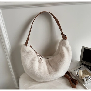 Detail of off-white faux fur crescent shoulder bag with brown leather strap in modern office setting