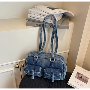 Detail of vintage blue denim shoulder bag featuring double front buckle pockets and texture