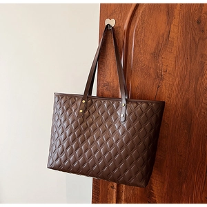 Detail of deep brown quilted tote bag with textured faux leather and metal rivets