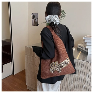 Detail of a brown knit tote bag featuring a leopard print Mama patch on model's shoulder