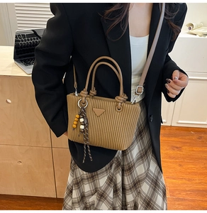 Détail de la texture en velours côtelé marron du sac avec logo et breloque en bois