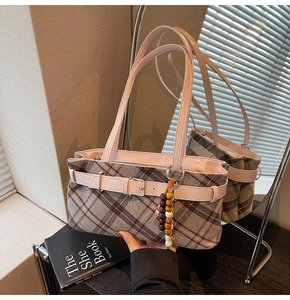 Detail of plaid handbag with pink leather trim and decorative wooden bead charm