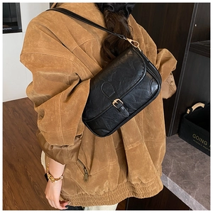 Close-up of black retro shoulder bag with wrinkled faux leather and gold buckle detail