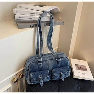 Detailed view of durable denim shoulder bag with dual front pockets and buckle straps