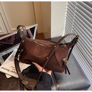 Detail view of deep brown suede dumpling bag featuring side fringe zippers and wide strap