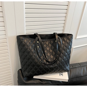Detail of black quilted tote bag featuring gold rivets and elegant diamond stitching