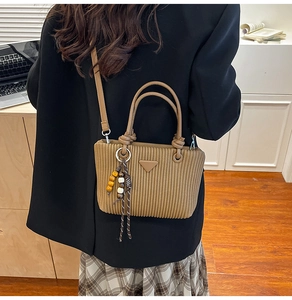 Détail du sac bandoulière en velours côtelé avec breloque en bois et plaque métal
