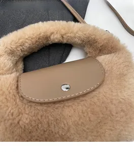 Détail d'un sac à main en peluche kaki avec rabat en cuir marron et boucle en métal