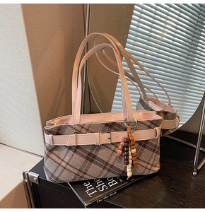Detail view of plaid underarm bag with pink leather strap and colorful wooden beads